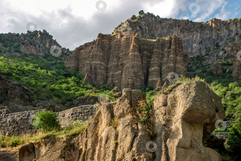 Скачать Величественные скальные образования в зеленом горном пейзаже под облачным небом фотосток Ozero