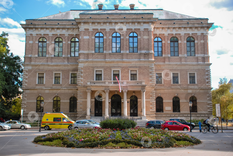 Скачать Историческое европейское здание с разноцветными автомобилями, припаркованными перед ним фотосток Ozero