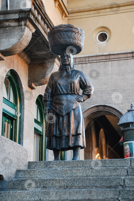 Скачать Бронзовая статуя продавщицы с корзиной на голове возле исторического здания фотосток Ozero