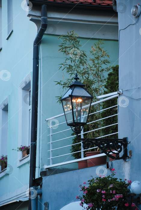 Скачать Очаровательный уличный фонарь на здании пастельных тонов с зеленью и цветами фотосток Ozero