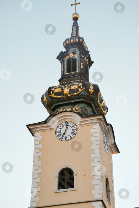 Скачать Элегантная церковная башня с часами и шпилем на фоне ясного голубого неба фотосток Ozero