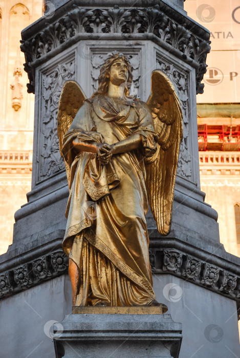 Скачать Золотая статуя ангела на богато украшенной колонне в элегантном драпированном одеянии фотосток Ozero