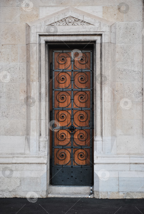 Скачать Богато украшенная готическая деревянная дверь с кованым узором на каменной стене здания фотосток Ozero
