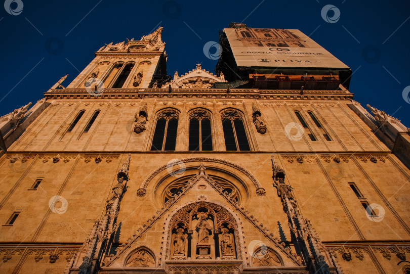 Скачать Залитый солнцем фасад готического собора на фоне ясного голубого неба фотосток Ozero