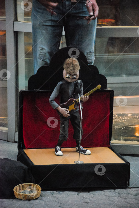 Скачать Уличное выступление кукольного музыканта с гитарой в городских условиях фотосток Ozero