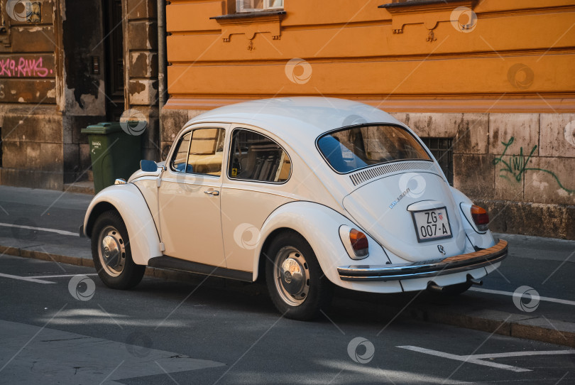 Скачать Старинный белый фольксваген-жук, припаркованный на городской улице фотосток Ozero