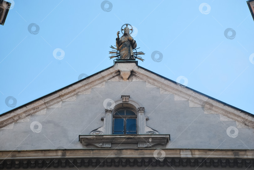 Скачать Исторический фасад церкви с религиозной статуей под ясным голубым небом фотосток Ozero