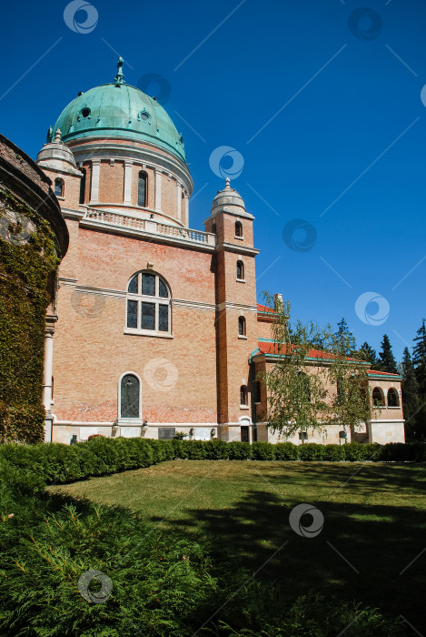 Скачать Историческое кирпичное здание с зеленым куполом в окружении пышного парка под голубым небом фотосток Ozero