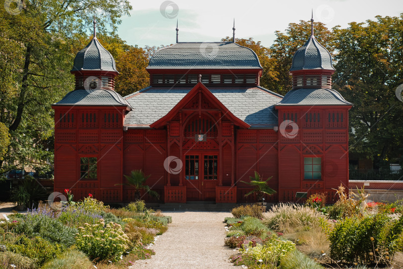 Скачать Богато украшенный павильон из красного дерева в викторианском стиле в окружении пышного сада фотосток Ozero