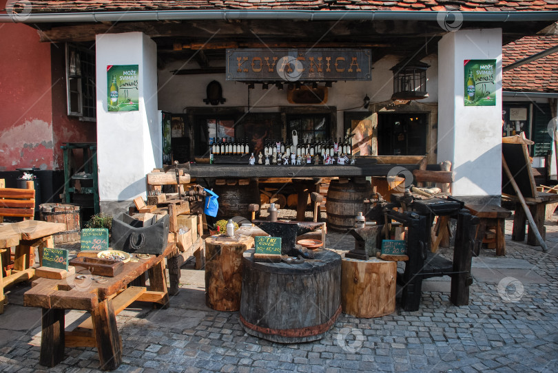 Скачать Открытый бар в деревенском стиле с деревянной мебелью и вывесками, выложенный булыжником фотосток Ozero