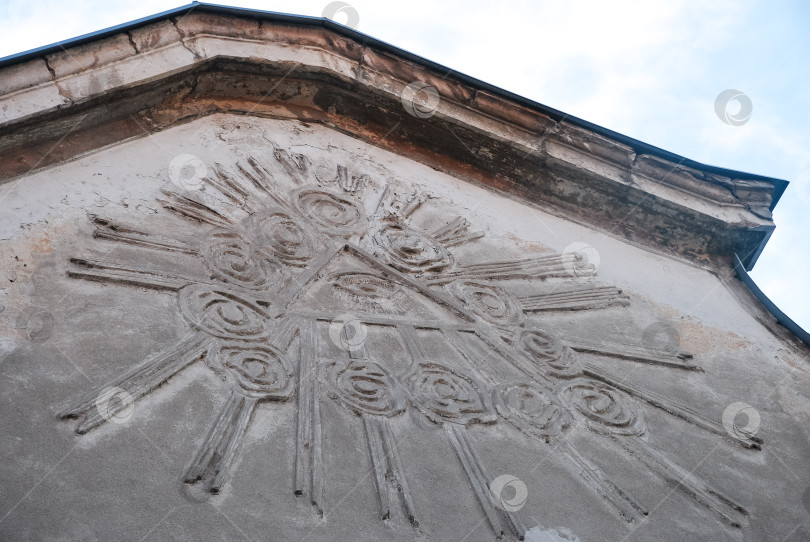 Скачать Фасад старого здания с рельефным рисунком в виде солнечных лучей под ясным небом фотосток Ozero