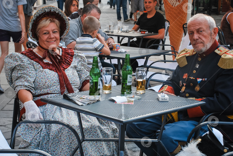 Скачать Зрелая кавказская пара в исторических костюмах сидит в уличном кафе фотосток Ozero