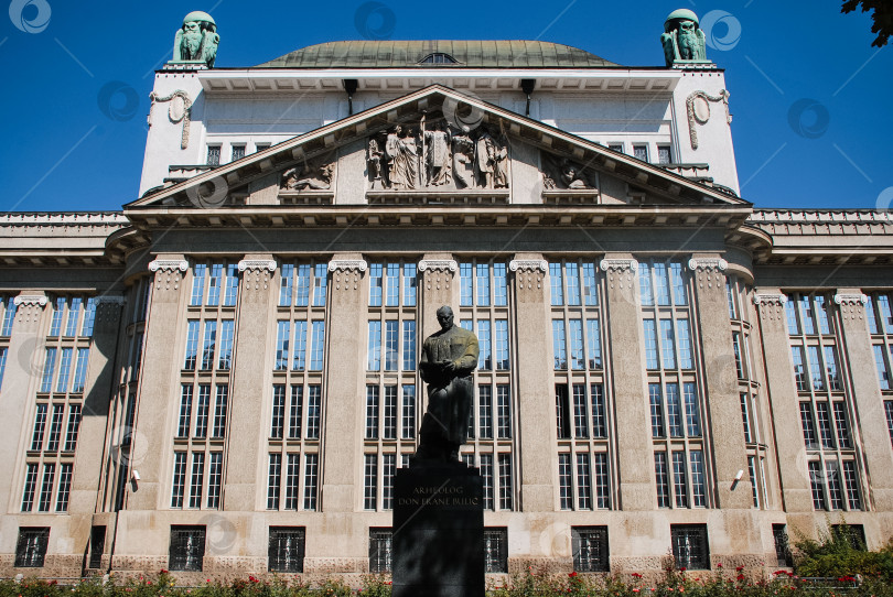 Скачать Историческое европейское здание со скульптурами и богато украшенной архитектурой под ясным голубым небом фотосток Ozero