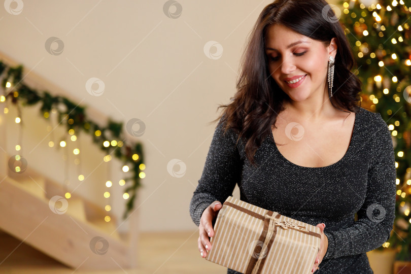 Скачать женщина в черном платье. Женщина улыбается и держит в руках подарок фотосток Ozero