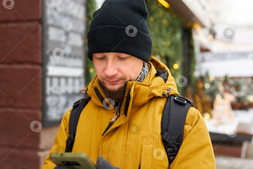 Скачать мужчина держит в руках смартфон, стоит на фоне городской улицы фотосток Ozero