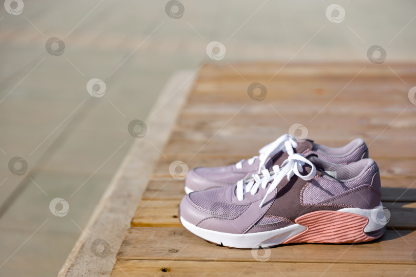 Скачать кроссовки стоят на деревянных досках на фоне брусчатки фотосток Ozero