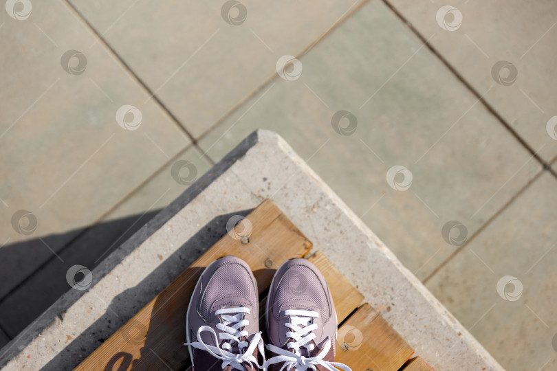 Скачать кроссовки стоят на деревянных досках на фоне брусчатки фотосток Ozero