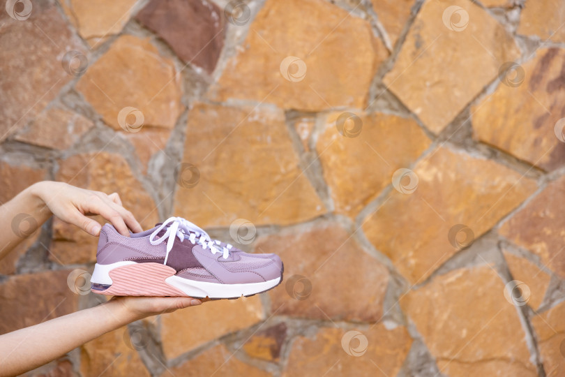 Скачать женщина держит в руках кроссовки. Место для текста фотосток Ozero