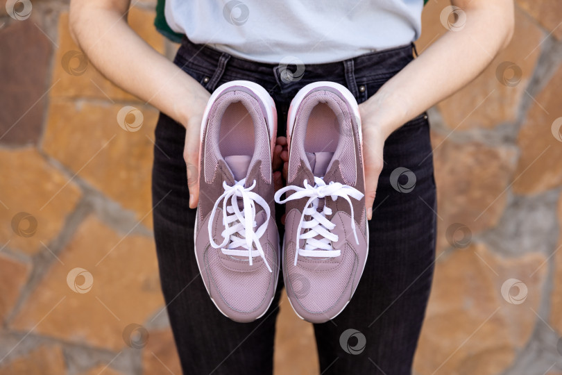 Скачать женщина держит в руках кроссовки. Место для текста фотосток Ozero