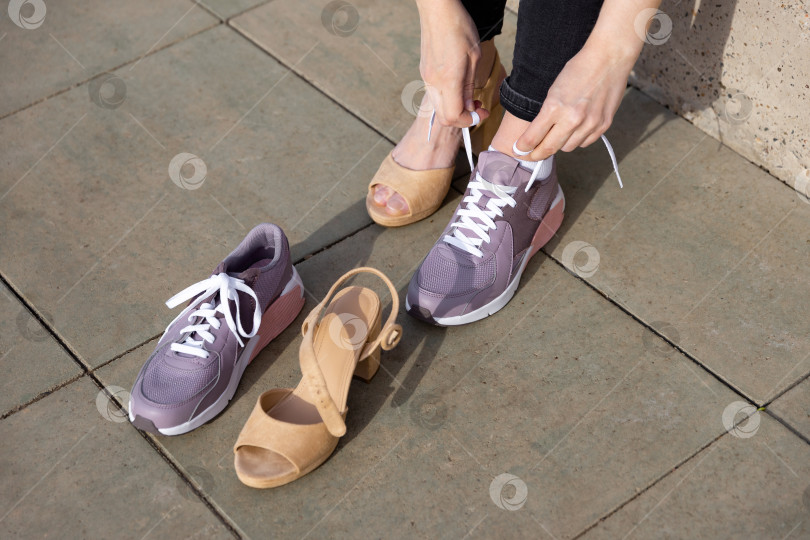 Скачать женщина снимает обувь и надевает кроссовки фотосток Ozero
