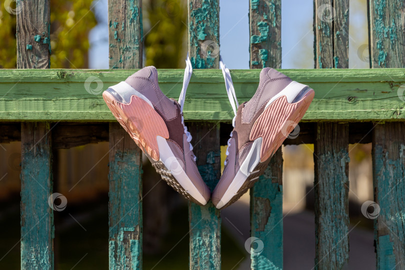 Скачать кроссовки висят на шнурках на старом деревянном заборе фотосток Ozero