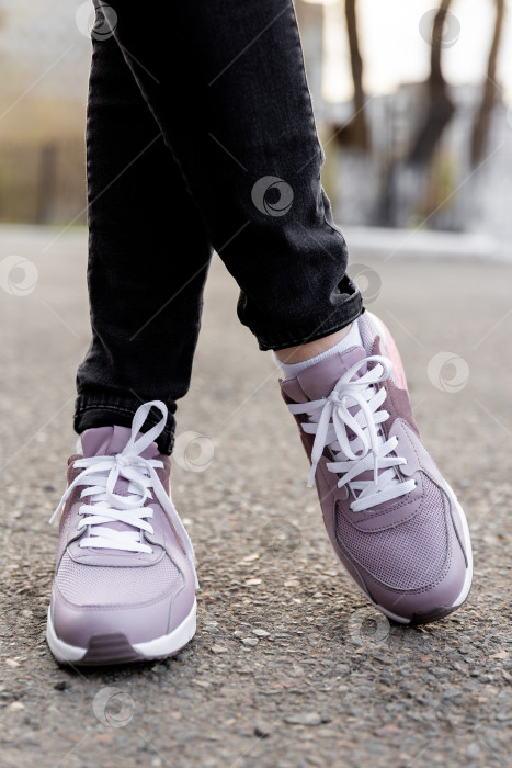 Скачать Женщина в джинсах и кроссовках стоит на тротуаре фотосток Ozero