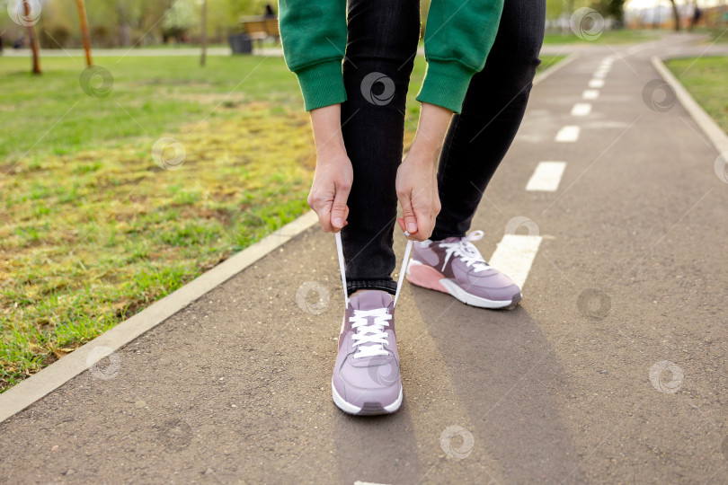 Скачать женщина в кроссовках стоит на дорожке и завязывает шнурки фотосток Ozero