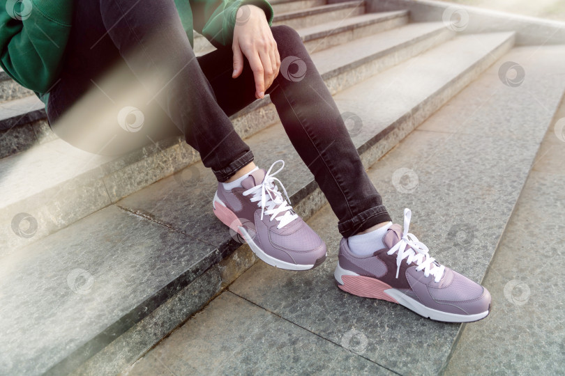 Скачать женщина в толстовке и джинсах сидит на лестнице фотосток Ozero