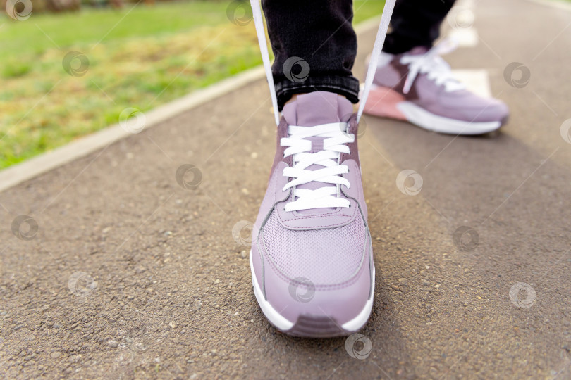 Скачать женщина в кроссовках стоит на дорожке и завязывает шнурки фотосток Ozero