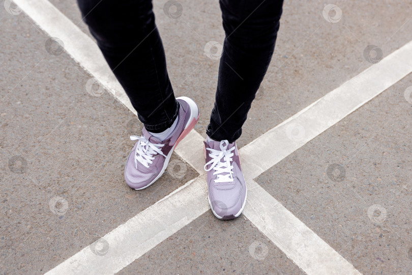 Скачать женщина в кроссовках стоит на пересеченной дорожной разметке фотосток Ozero