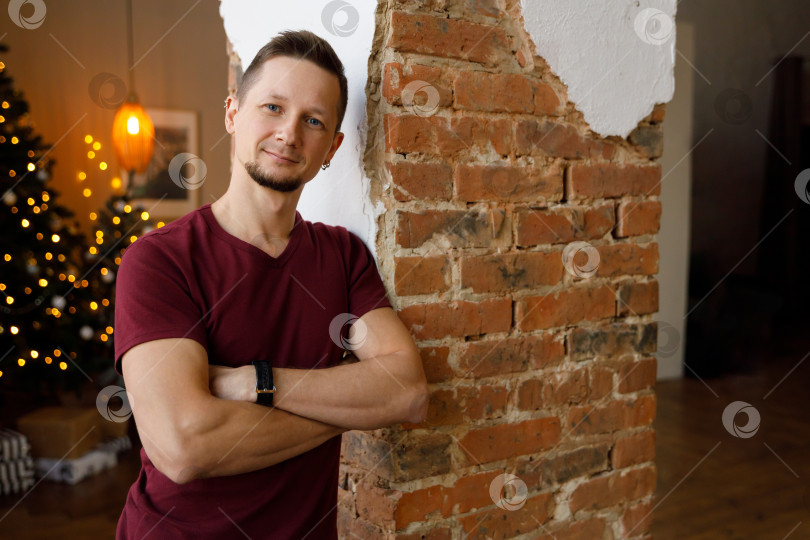 Скачать мужчина стоит возле кирпичной колонны, скрестив руки на груди фотосток Ozero