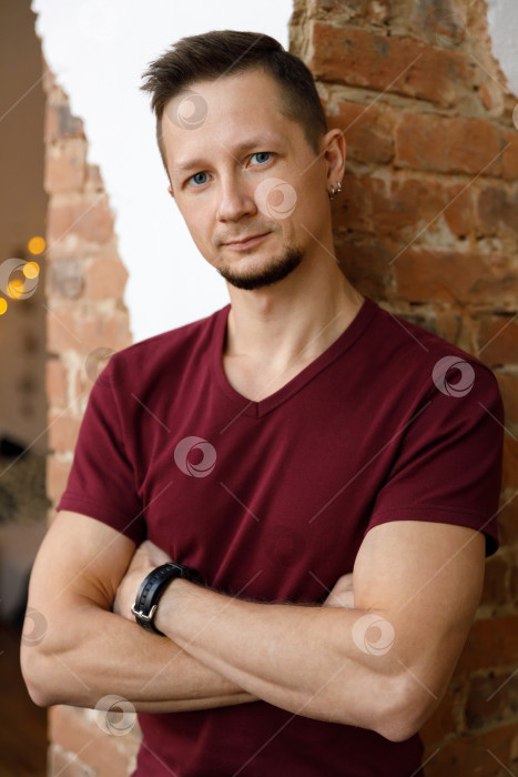 Скачать мужчина стоит возле кирпичной колонны, скрестив руки на груди фотосток Ozero