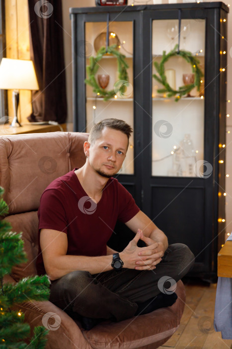 Скачать мужчина сидит в кресле в комнате, украшенной к Рождеству фотосток Ozero
