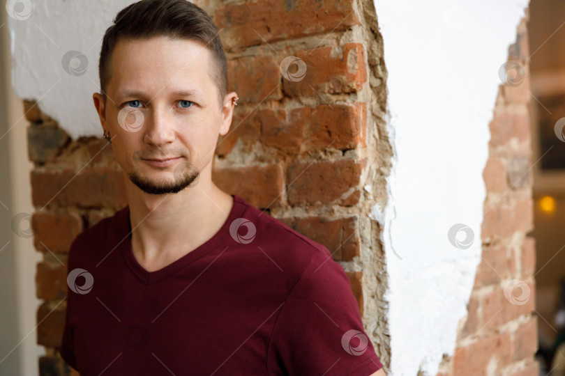 Скачать портрет бородатого брюнета крупным планом в футболке на фоне кирпичной стены фотосток Ozero