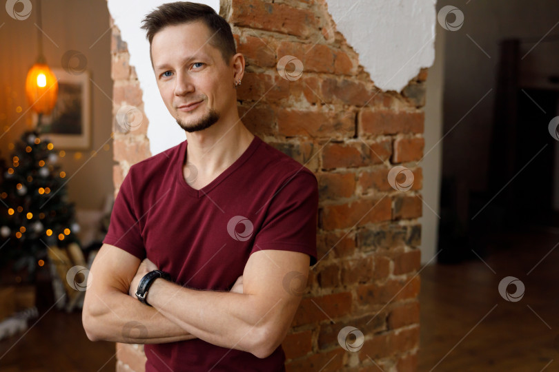 Скачать мужчина стоит возле кирпичной колонны, скрестив руки на груди фотосток Ozero