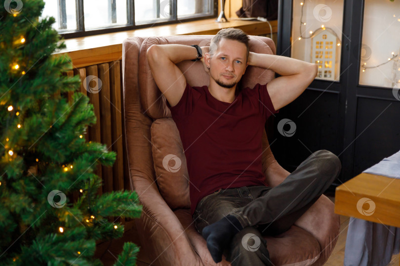 Скачать мужчина сидит в кресле в комнате, украшенной к Рождеству фотосток Ozero