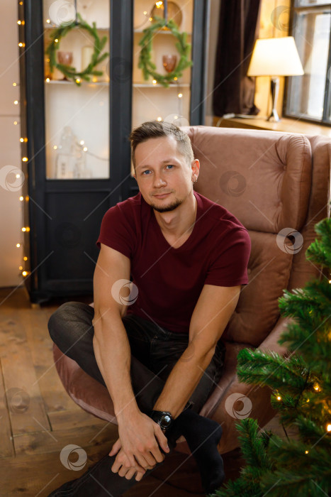Скачать мужчина сидит в кресле в комнате, украшенной к Рождеству фотосток Ozero