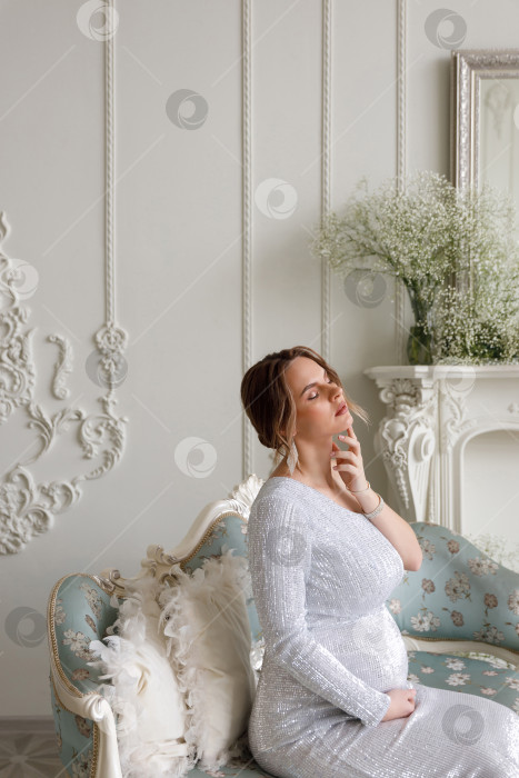 Скачать беременная женщина в платье сидит на диване фотосток Ozero