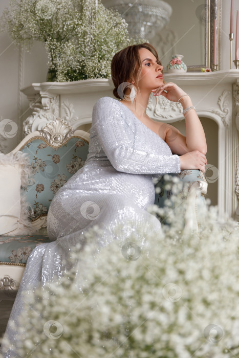 Скачать беременная женщина в платье сидит на диване фотосток Ozero