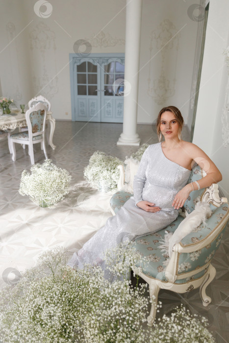 Скачать беременная женщина в платье сидит на диване фотосток Ozero