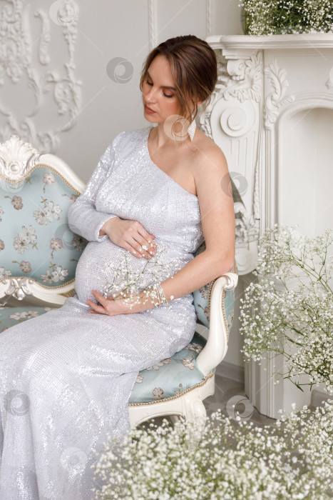 Скачать беременная женщина в платье сидит на диване фотосток Ozero