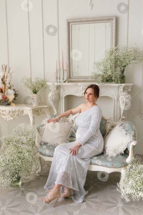 Скачать беременная женщина в платье сидит на диване фотосток Ozero