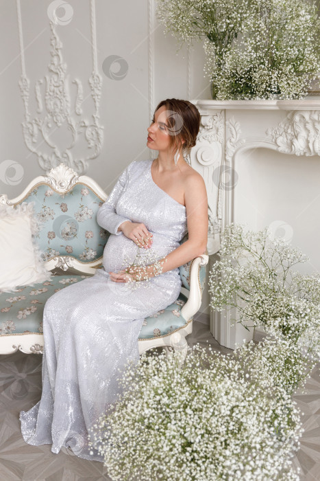 Скачать беременная женщина в платье сидит на диване фотосток Ozero