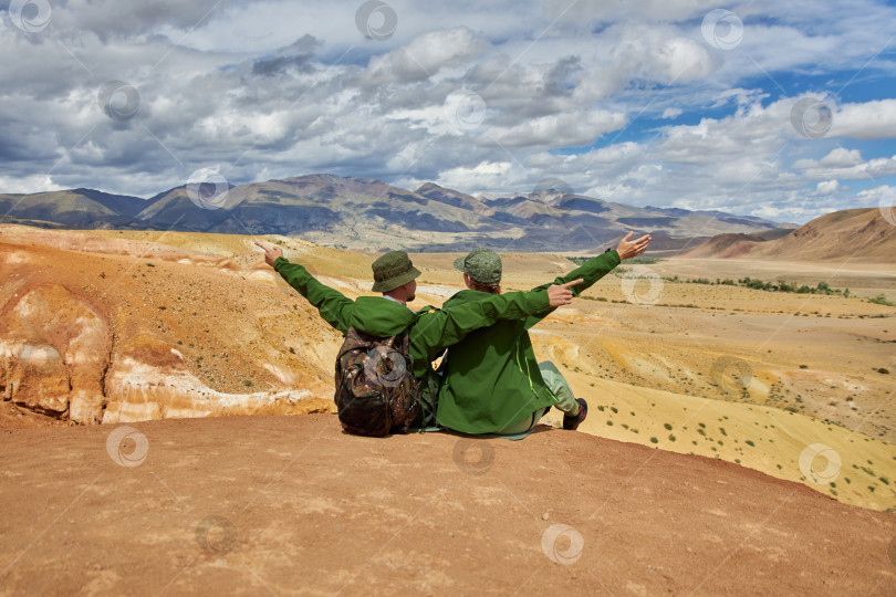 Скачать пара туристов сидит спиной к камере на фоне пейзажа фотосток Ozero