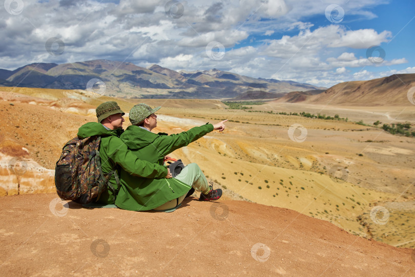 Скачать пара туристов сидит спиной к камере на фоне пейзажа фотосток Ozero