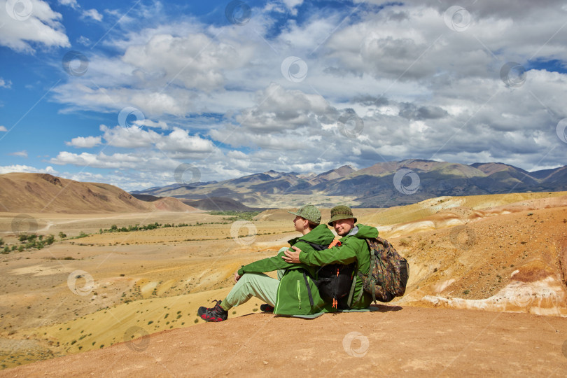 Скачать пара туристов сидит спиной к камере на фоне пейзажа фотосток Ozero