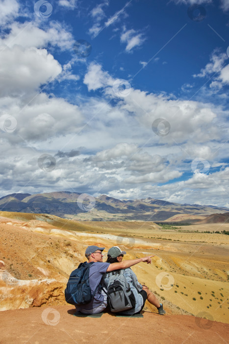 Скачать пара туристов сидит спиной к камере на фоне пейзажа фотосток Ozero