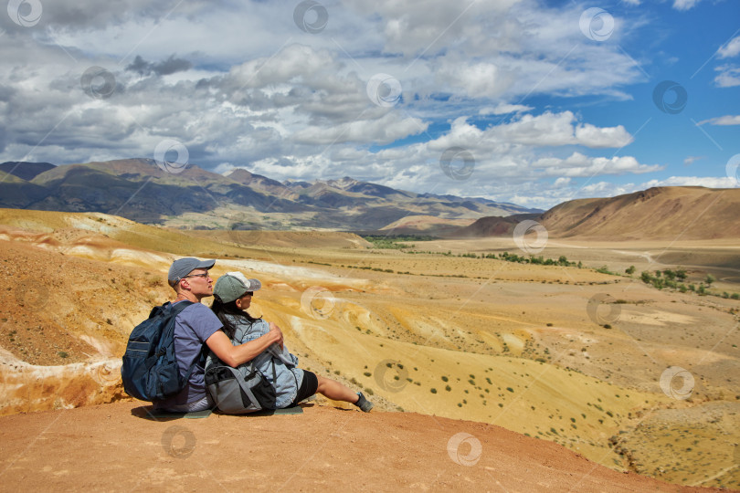 Скачать пара туристов сидит спиной к камере на фоне пейзажа фотосток Ozero