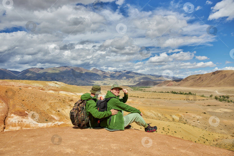 Скачать пара туристов сидит спиной к камере на фоне пейзажа фотосток Ozero