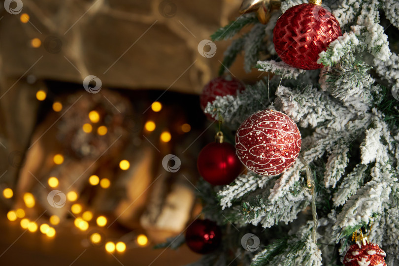 Скачать Новогодние игрушки-шары висят на еловой ветке на фоне камина фотосток Ozero